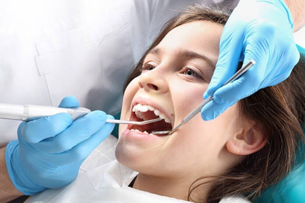 nina en consulta dental recibiendo revision con dentista en clinica tres olivos